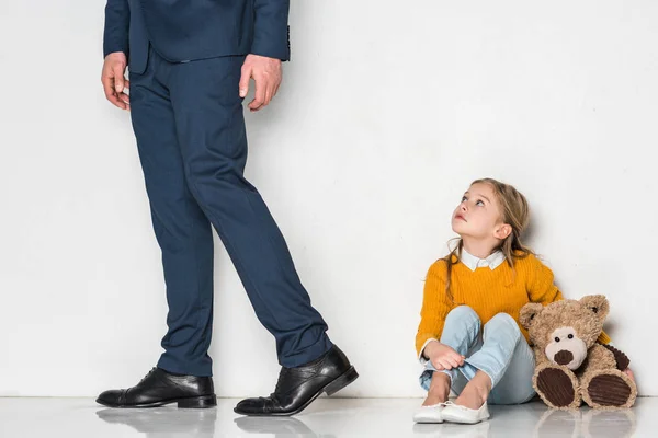 Aufgebrachte Tochter sieht Vater im Geschäftsanzug vereinzelt auf grauem Grund davonlaufen — Stockfoto