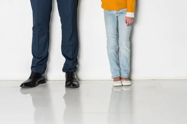 Visión parcial de la hija y el padre en traje de negocios tomados de la mano aislados en gris - foto de stock