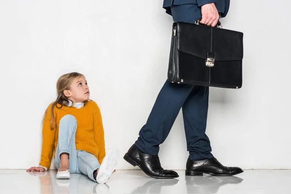 Aufgebrachte Tochter sieht Vater im Geschäftsanzug vereinzelt auf grauem Grund davonlaufen — Stockfoto