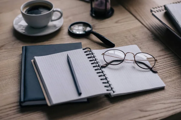 Close-up shot of notebooks and cup of coffee on work desk — Stock Photo