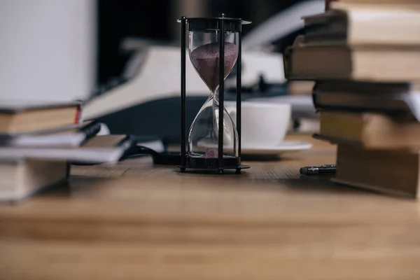 Gros plan de sablier et de livres empilés — Photo de stock