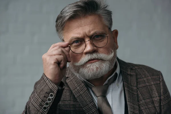 Serio hombre mayor en traje de tweed y gafas mirando a la cámara - foto de stock