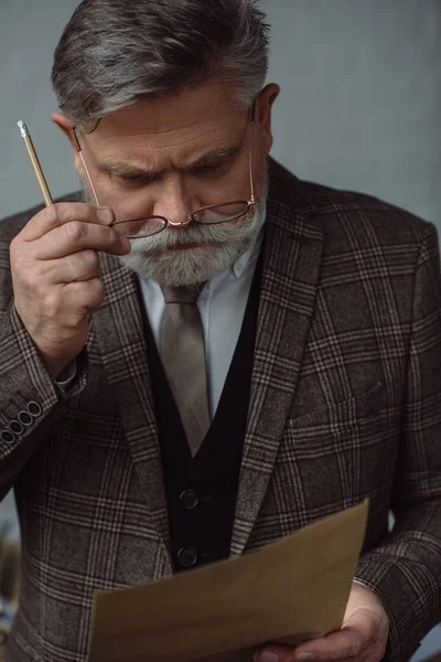 Homem sênior pensativo com lápis e folha de papel — Fotografia de Stock