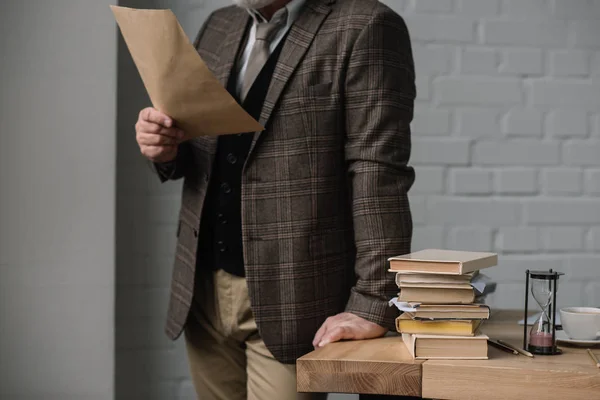 Cropped shot of man reading letter while leaning at work desk — Stock Photo