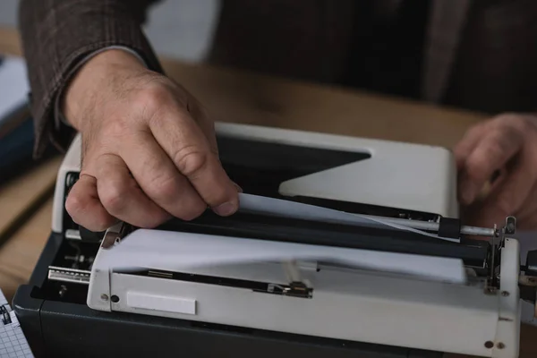 Abgeschnittene Aufnahme eines Schreibers, der Papier in Schreibmaschine lädt — Stockfoto