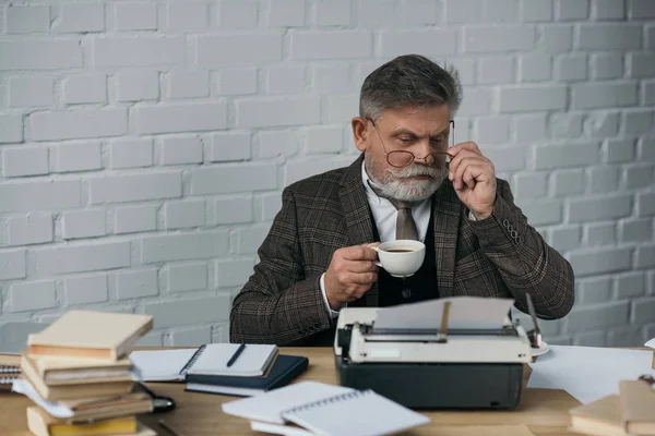 Gutaussehende Seniorin trinkt Kaffee am Arbeitsplatz — Stockfoto