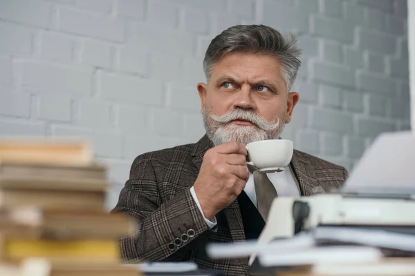 Bärtige Seniorin trinkt Kaffee am Arbeitsplatz — Stockfoto