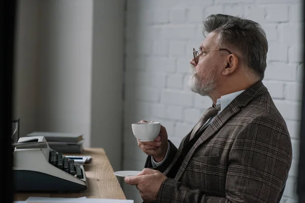 Bello scrittore anziano in tuta tweed bere caffè sul posto di lavoro — Foto stock