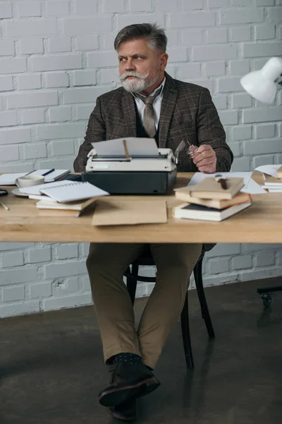 Handsome senior writer in tweed suit working with typewriter — Stock Photo