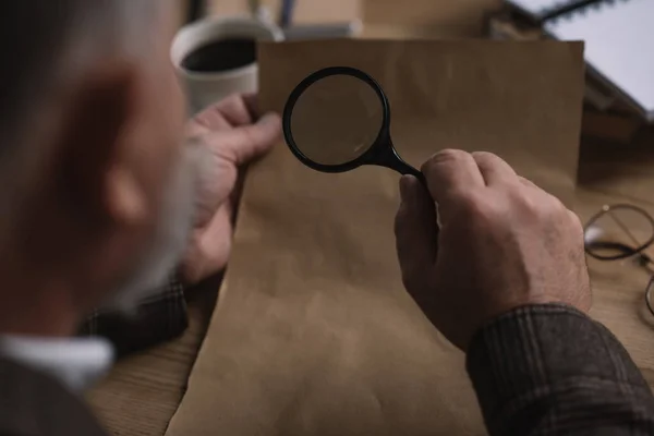 Close-up shot of senior man reading letter with magnifying glass — Stock Photo