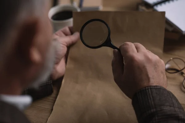 Plan rapproché d'un homme âgé lisant une lettre avec une loupe — Photo de stock