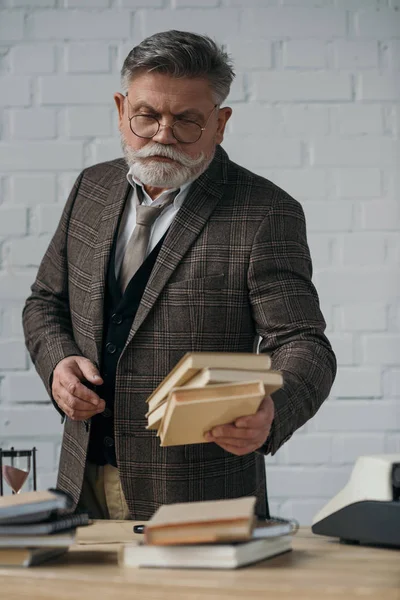 Pensoso anziano scrittore holding pila di libri — Foto stock