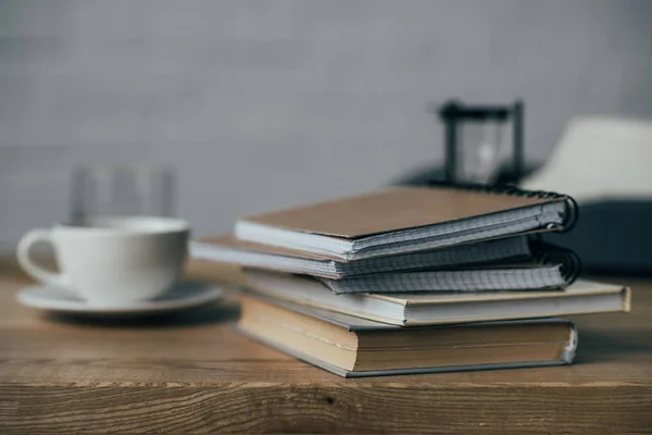 Cup of coffee and stack of notebooks on work desk — Stock Photo