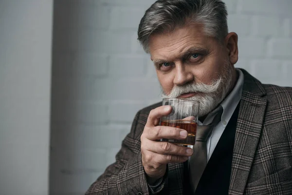 Portrait en gros plan d'un homme âgé en costume de tweed avec un verre de whisky — Photo de stock