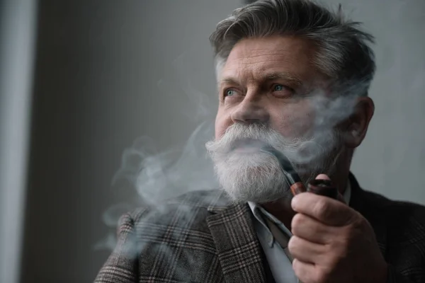 Primer plano retrato de barbudo hombre mayor fumar pipa - foto de stock