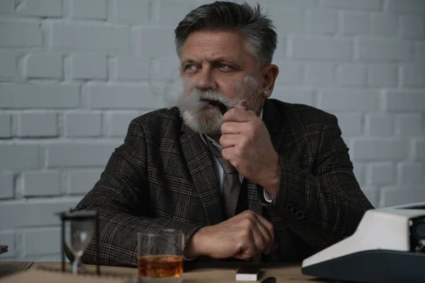 Handsome senior writr smoking pipe at workplace — Stock Photo