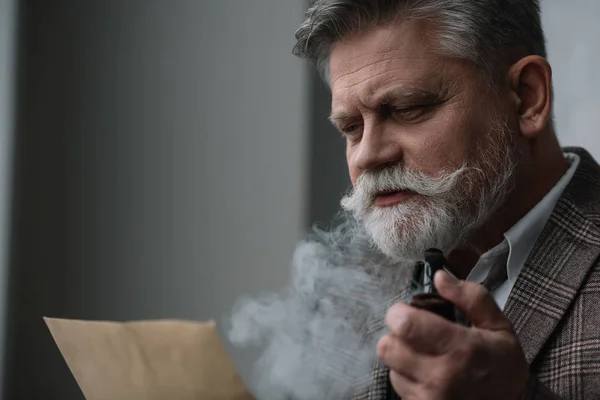 Bearded senior man smoking pipe and reading letter — Stock Photo