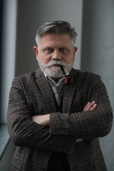 Senior man in tweed costume smoking pipe and looking at camera — Stock Photo