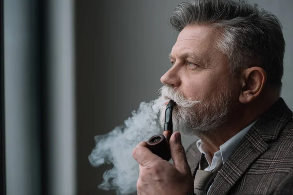 Bearded senior man in tweed costume smoking pipe — Stock Photo