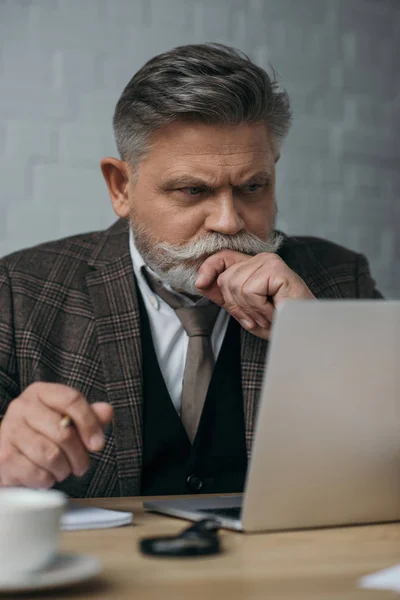 Nachdenklicher Senior schaut auf Laptop — Stockfoto