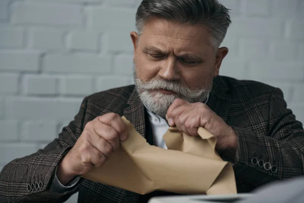 Close-up portrait of disappointed senior writer tearing his manuscript — Stock Photo