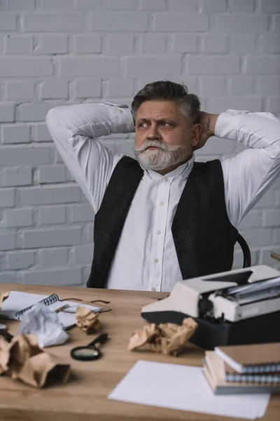 Handsome senior writer relaxing at messy workplace — Stock Photo