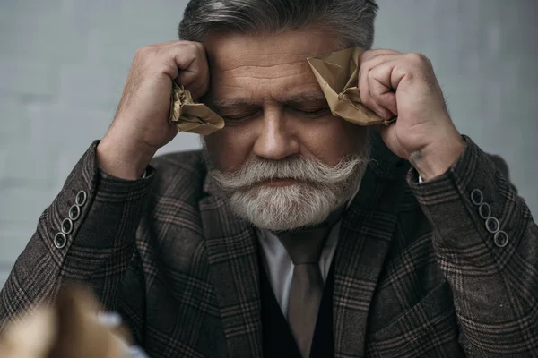 Depressed senior man with crumpled papers in hands — Stock Photo