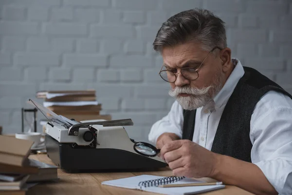 Escritor senior reescribir manuscrito con máquina de escribir - foto de stock