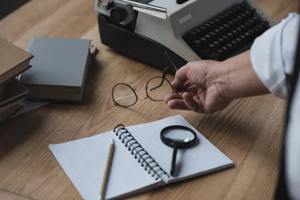 Escritor sênior colocando óculos na mesa de trabalho — Fotografia de Stock