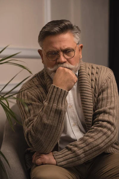 Thoughtful senior man sitting in armchair — Stock Photo