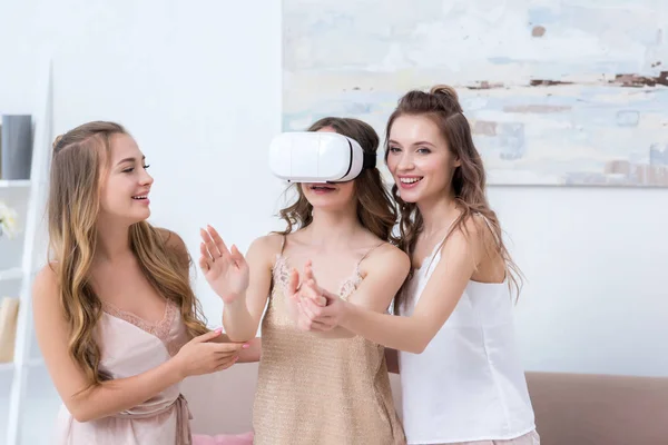 Hermosas mujeres jóvenes en pijama divirtiéndose con auriculares de realidad virtual - foto de stock