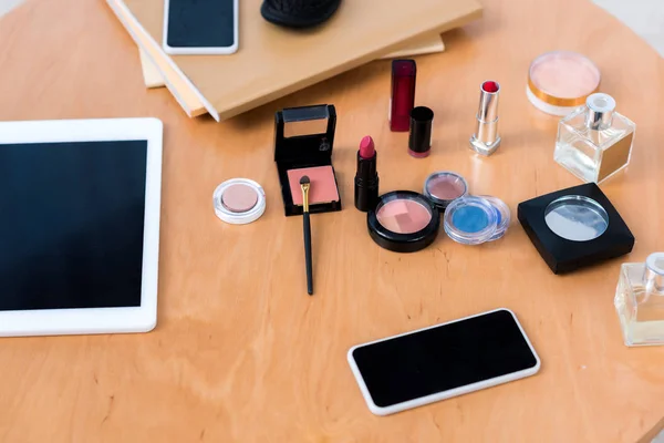 Vista superior de los dispositivos digitales y diversos cosméticos en la mesa - foto de stock