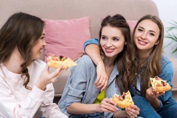 Hermosas novias sonrientes comiendo pizza y hablando en casa - foto de stock