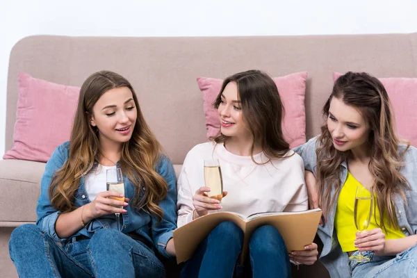 Schöne, glückliche Freundinnen, die gemeinsam Champagner trinken und Zeitschrift lesen — Stockfoto
