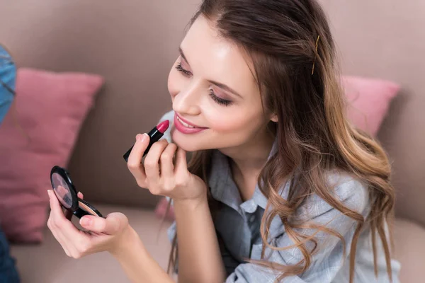 Beautiful smiling young woman applying lipstick — Stock Photo