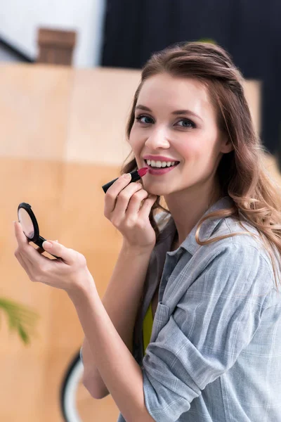 Bella giovane donna che applica il trucco e sorride alla fotocamera — Foto stock