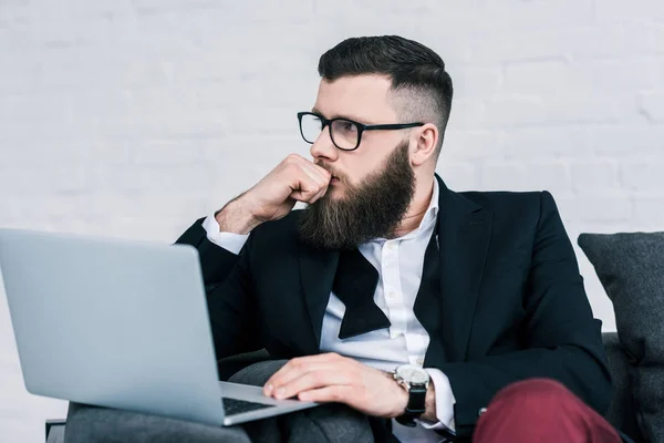 Portrait of pensive businessman with laptop looking away — Stock Photo