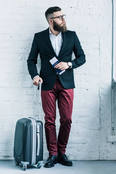 Thoughtful businessman with passport, ticket and baggage looking away — Stock Photo