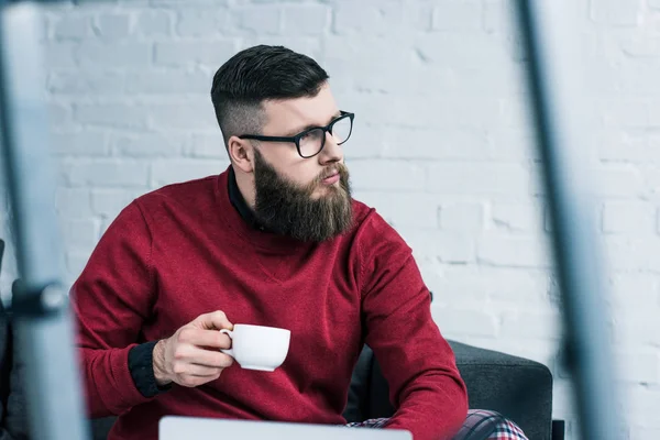 Porträt eines nachdenklichen Geschäftsmannes mit Brille und einer Tasse Kaffee, der wegschaut — Stockfoto