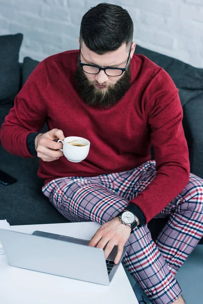 Vista de ángulo alto de hombre de negocios con taza de café utilizando el ordenador portátil - foto de stock