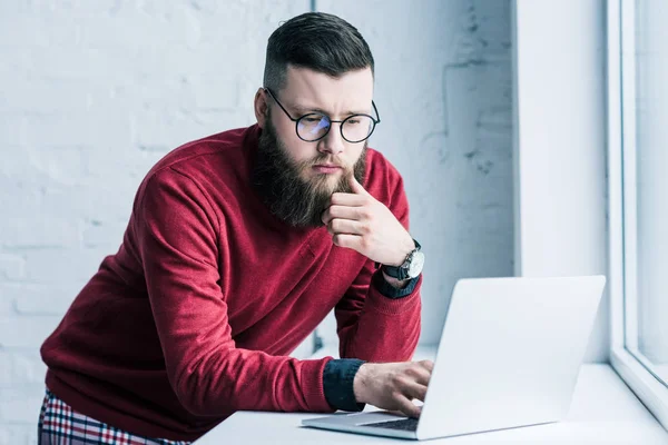 Portrait of concentrated businessman in eyeglasses working on laptop — Stock Photo