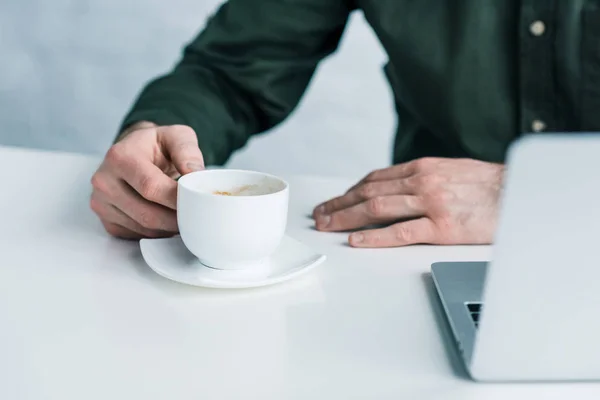 Tiro cortado de homem de negócios com xícara de café no local de trabalho — Fotografia de Stock