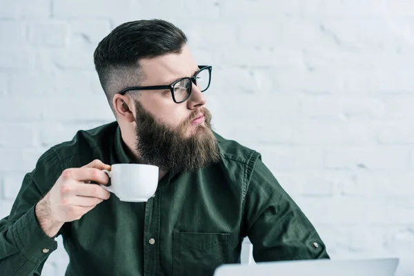 Portrait of pensive businessman holding cup of coffee in hand — Stock Photo