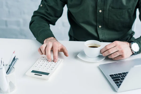 Partial view of businessman making calculations at workplace with cup of coffee — Stock Photo