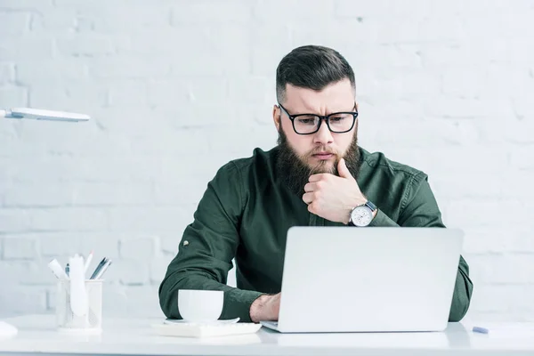 Retrato del empresario centrado que trabaja en el ordenador portátil en el lugar de trabajo - foto de stock