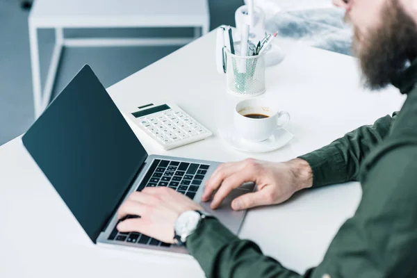 Partial view of businessman working on laptop with blank screen at workplace — Stock Photo