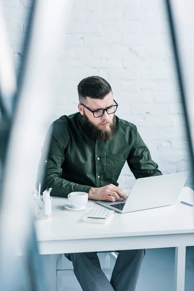 Porträt eines fokussierten Geschäftsmannes, der am Arbeitsplatz am Laptop arbeitet — Stockfoto