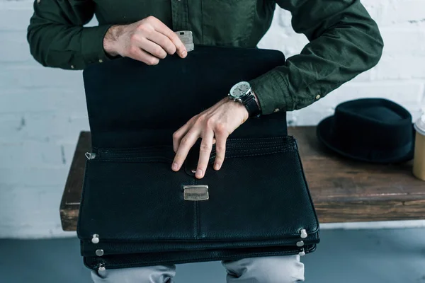 Cropped shot of businessman with opened suitcase sitting on wooden bench — Stock Photo