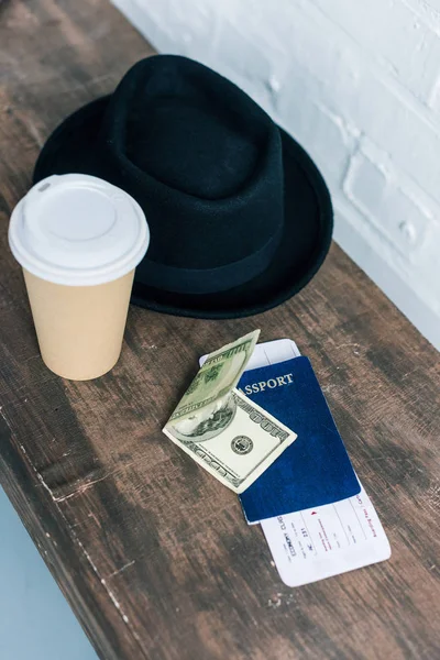 Vista de perto do passaporte arranjado, dinheiro, café para ir e chapéu no banco de madeira — Fotografia de Stock