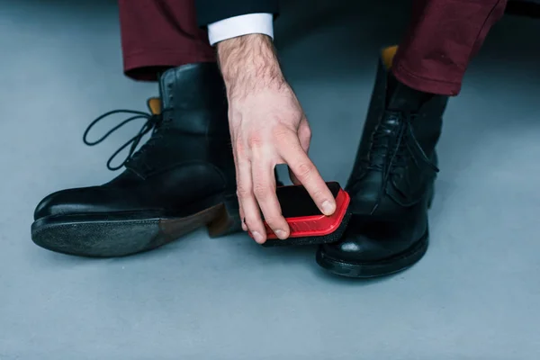 Partial view of businessman cleaning stylish black shoes — Stock Photo